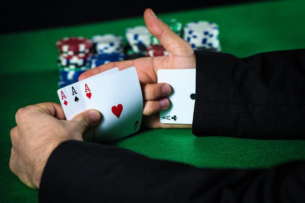 Man with ace up his sleeve, cheating at poker.